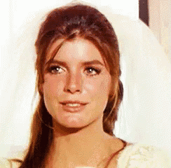 a close up of a woman 's face with long hair and a white dress .