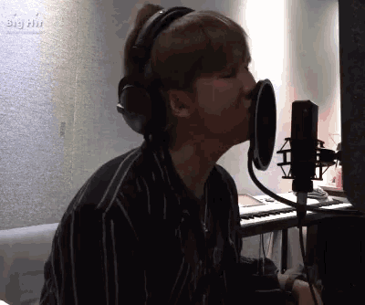 a man is singing into a microphone while wearing headphones .