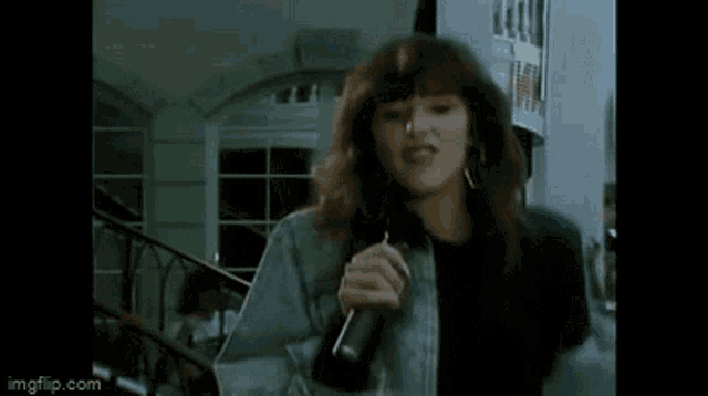 a woman is singing into a microphone while standing in front of a crowd .