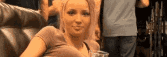 a woman is sitting on a couch holding a glass of beer and looking at the camera .