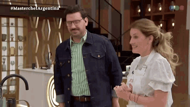 a man and a woman are standing next to each other in a kitchen with the words masterchef argentina on the bottom