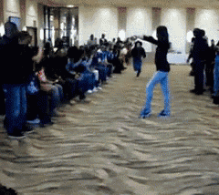 a woman is dancing in front of a crowd in a large room