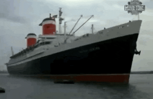 a large ship is docked in a body of water with a movie time sign in the background .