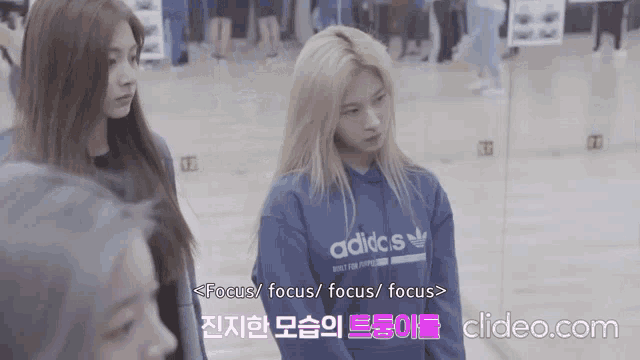 a girl wearing a blue adidas sweatshirt is standing next to another girl