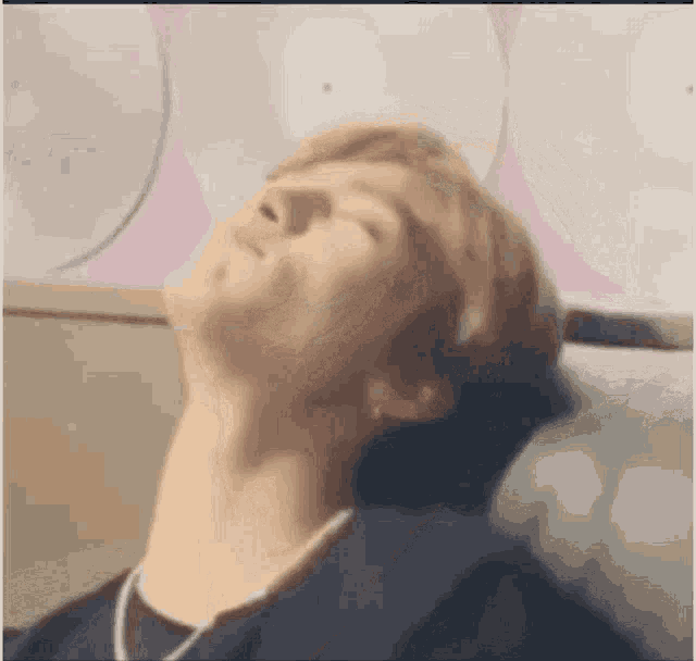 a young man is laying on a couch with his eyes closed and his head resting on a pillow .