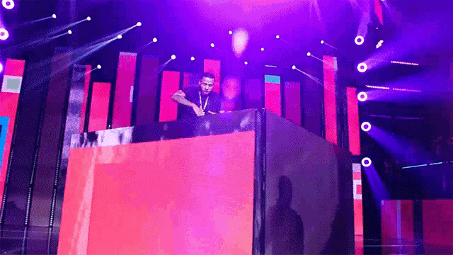 a man is playing music on a stage in front of purple lights