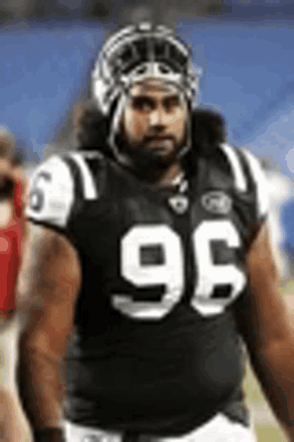 a football player wearing a helmet and number 96 jersey is standing on the field .