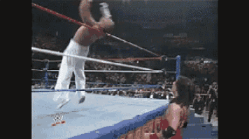a wrestler is doing a flip in a wrestling ring .