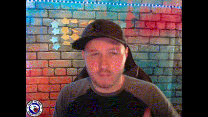 a man wearing a hat stands in front of a colorful brick wall