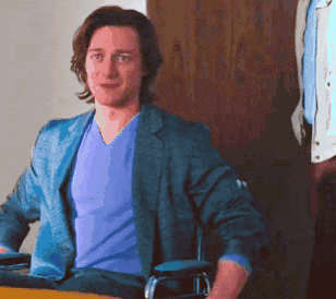 a man wearing a blue jacket and a purple shirt is sitting in a chair