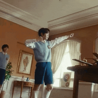 a boy in a blue vest and shorts is dancing