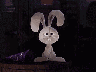 a stuffed bunny rabbit is sitting on a wooden table in a dark room .