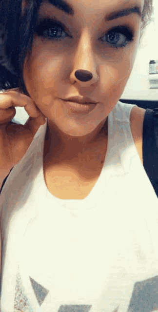 a close up of a woman 's face with a white tank top with the letter a on it