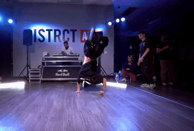 a man doing a handstand in front of a sign that says district a