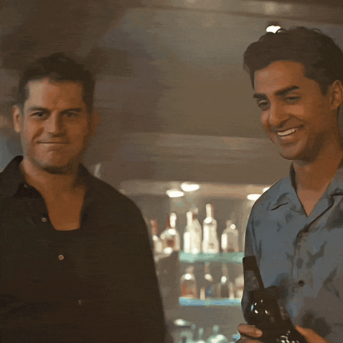 two men are standing next to each other smiling and holding bottles