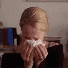 a woman is blowing her nose with a tissue .