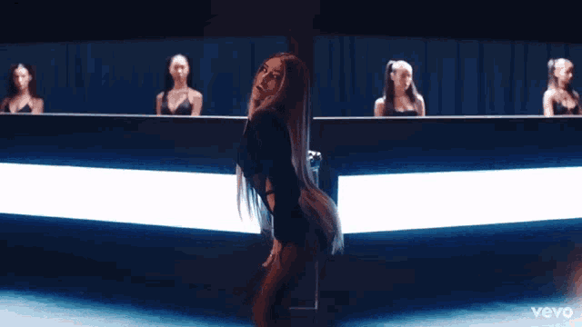 a woman in a black bodysuit is dancing in front of a group of women with the word vevo on the bottom