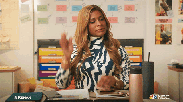 a woman sitting at a desk with a notebook that says ' kenan ' on it