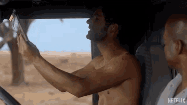a shirtless man taking a picture of himself in a car with netflix written on the bottom right