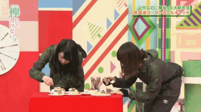 two women are standing next to each other on a table with plates of food on it