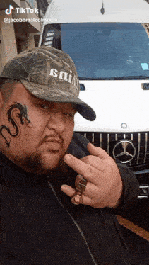 a man with a tattoo on his face is standing in front of a mercedes