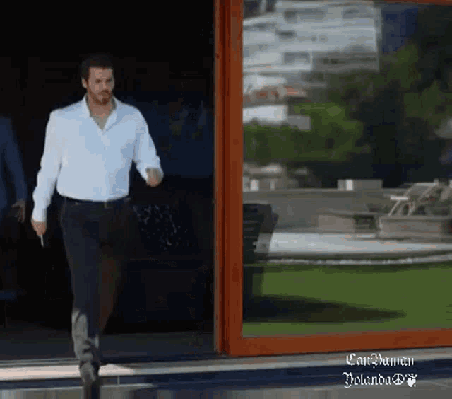 a man in a white shirt and black pants is walking through a sliding glass door ..