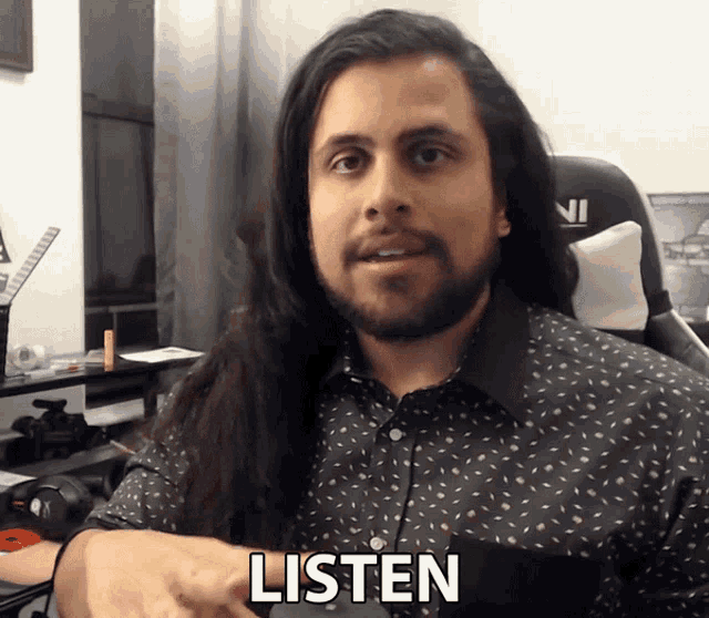 a man with long hair and a beard has the word listen written on his shirt
