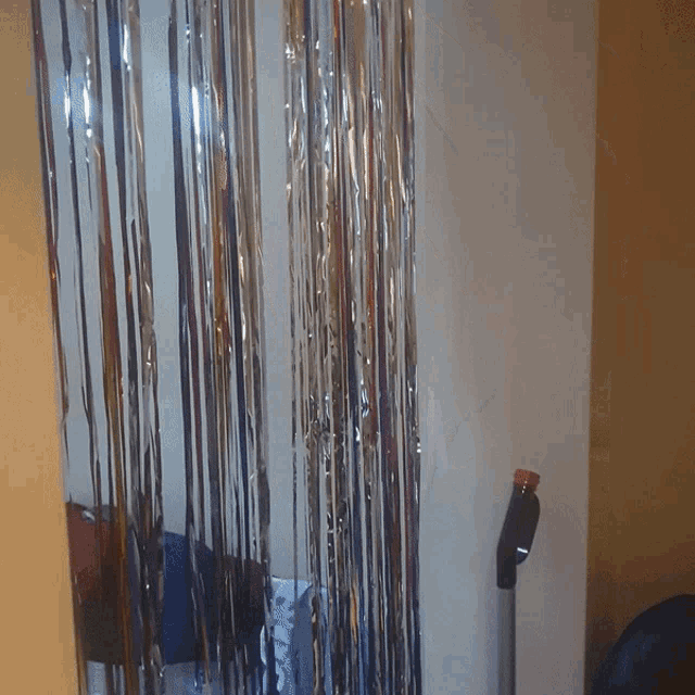 a silver tinsel curtain hangs on a white wall