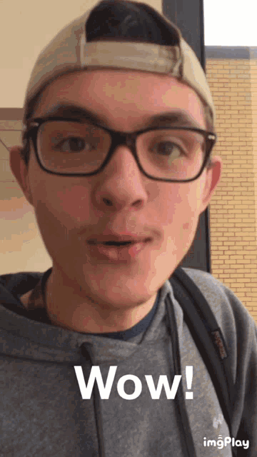 a man wearing glasses and a hat says wow on a screen