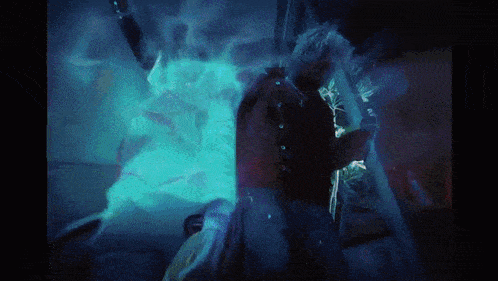 a person standing in a dark room with a blue light coming out of it