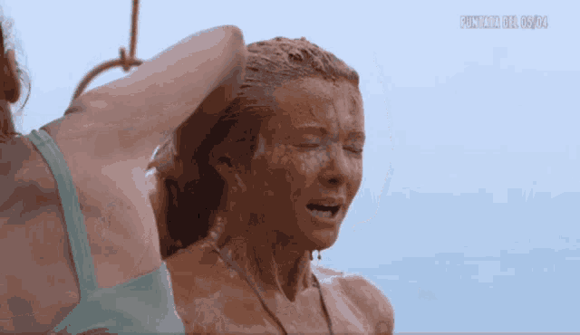 a woman in a bikini is covered in mud and has the word premium on the bottom right