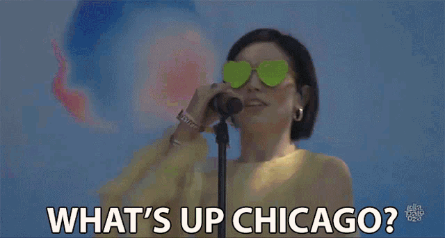 a woman singing into a microphone with the words what 's up chicago behind her
