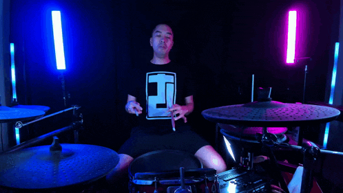 a man playing drums with a shirt that says t on it