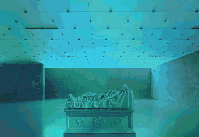 a statue of a person laying on a bed in a room