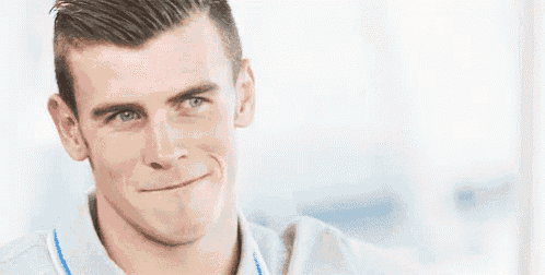 a man is smiling and making a funny face while wearing a grey shirt .