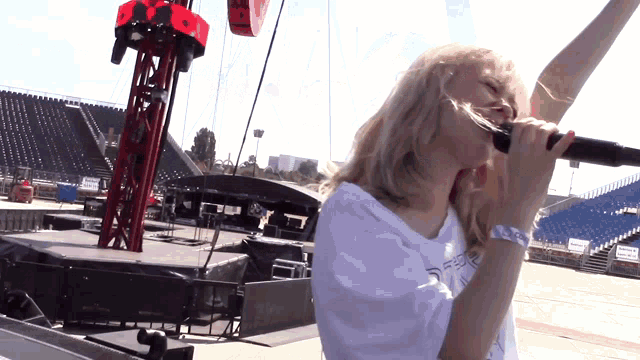 a woman singing into a microphone with a wristband that says ' ee ' on it
