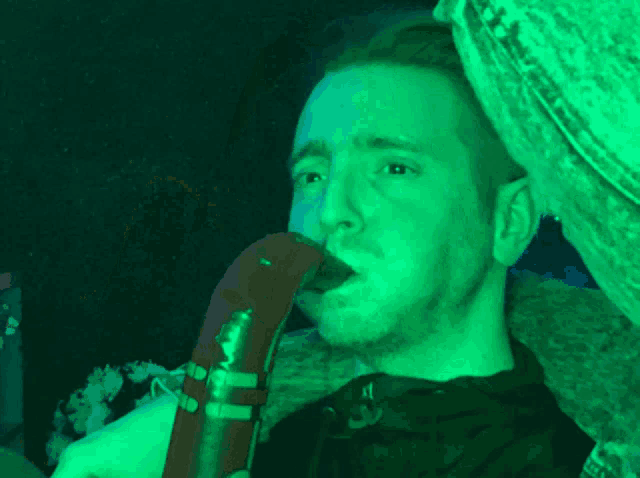 a man singing into a microphone in a dark room with green lights
