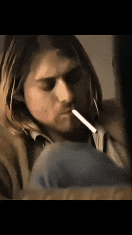 a man with long hair smoking a cigarette