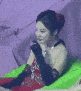 a woman sitting on a green pillow with the word love on her shirt