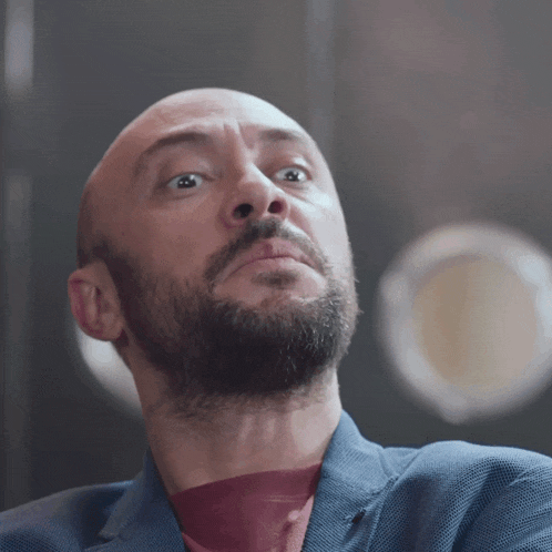 a bald man with a beard looks up at the sky