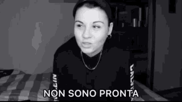 a black and white photo of a woman sitting on a bed with the words non sono pronta below her