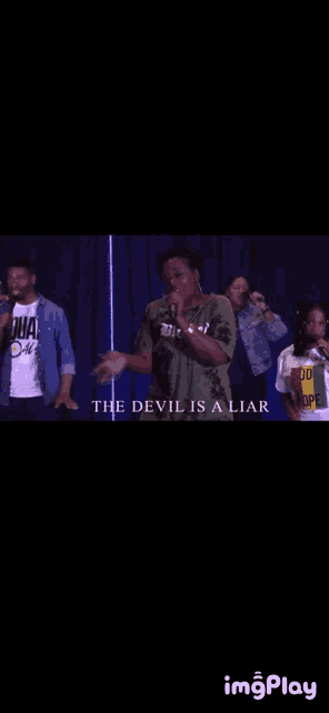 a group of people are standing in front of a blue curtain with the words " the devil is a liar " on the bottom