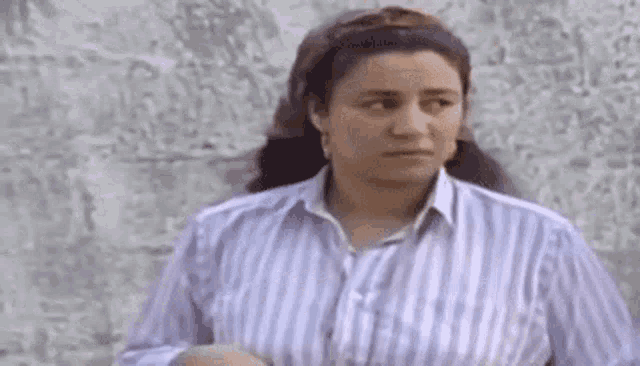 a woman wearing a striped shirt is standing in front of a wall .