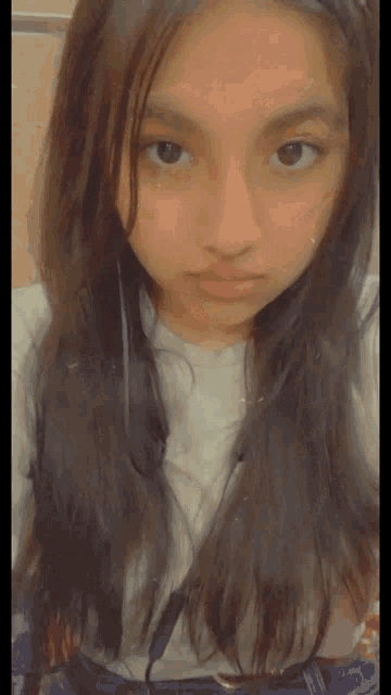 a young girl with long dark hair is taking a selfie