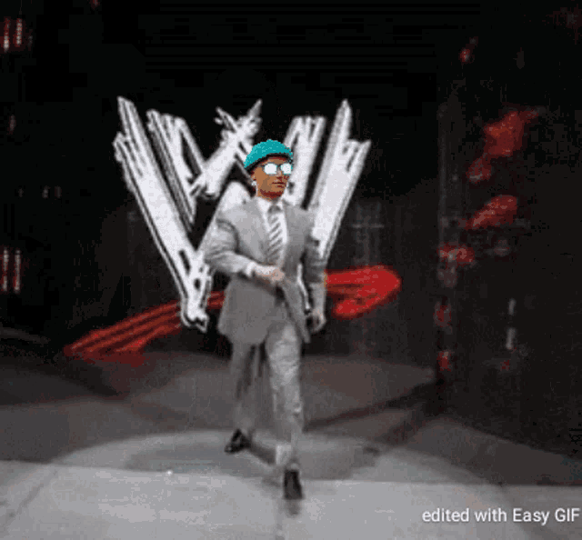 a man in a suit and tie is walking in front of a wrestling logo