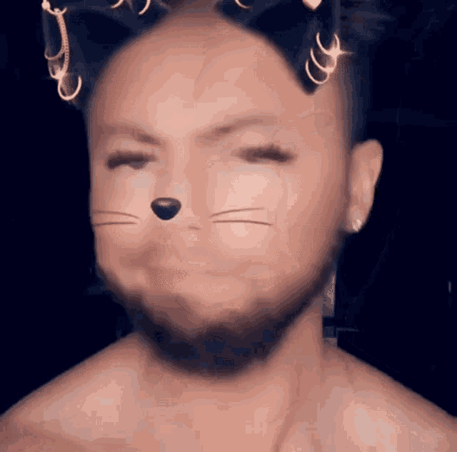 a man with a beard and cat ears on his head is making a funny face .