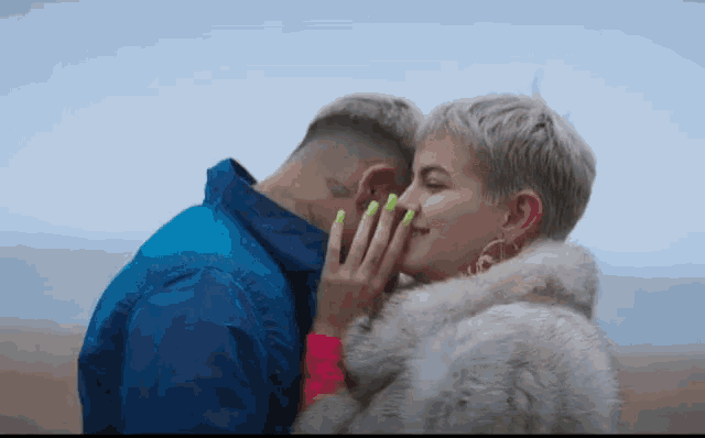 a woman with neon green nails kisses a man
