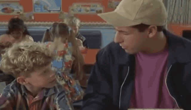 a man and a boy are sitting at a table in a classroom .