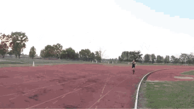 a man is dancing on a track in front of a stadium .