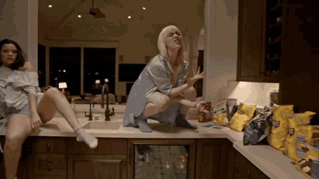 a woman squatting on a counter next to a bag of fritos